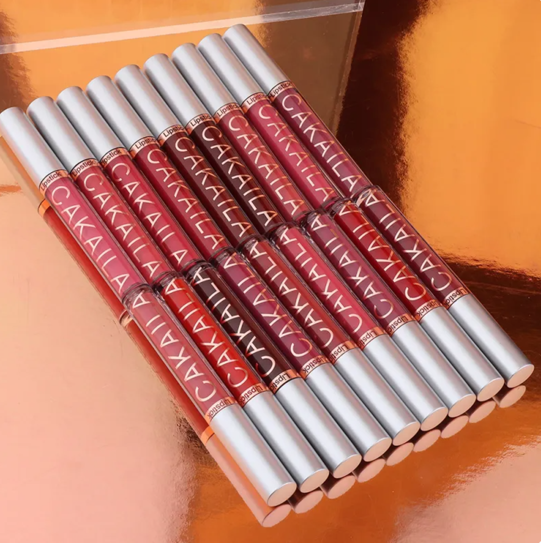 Row of VelvetGlow™ lip colors in red and pink shades with silver caps on a copper background