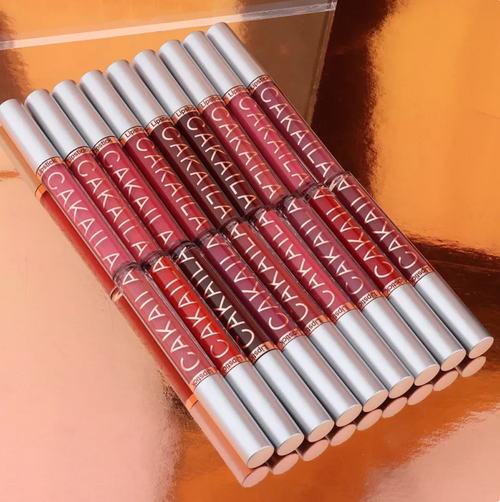 Row of VelvetGlow™ lip colors in red and pink shades with silver caps on a copper background