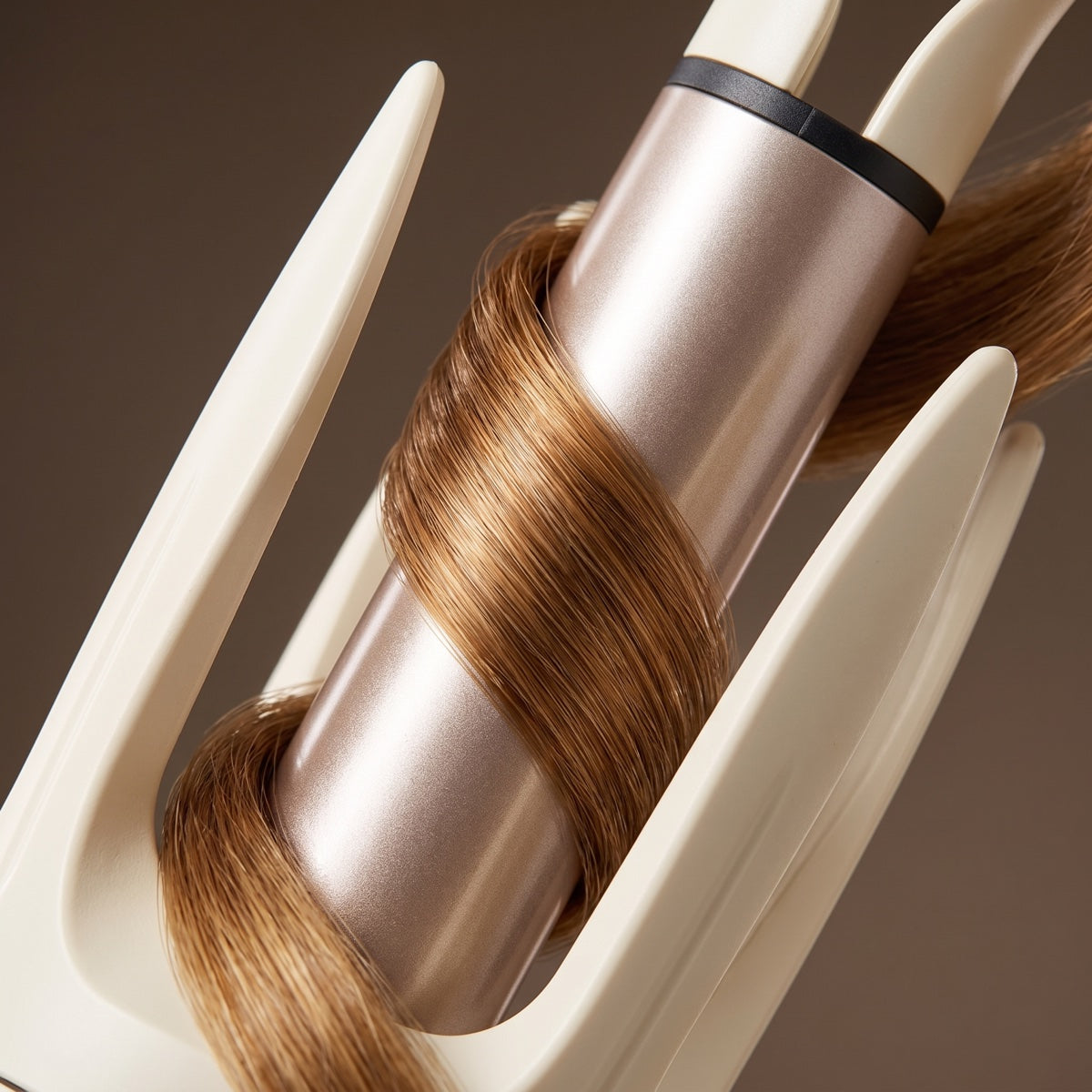 Light brown hair wrapped around the rose-gold rotating barrel of the CurlMuse™ automatic styling wand