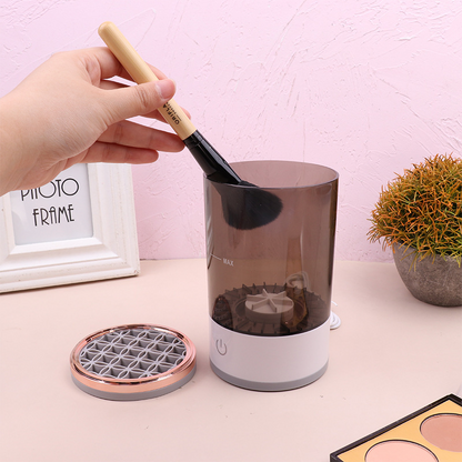 Hand cleaning a makeup brush inside the SwiftClean™ electric brush cleaner on a pink tabletop